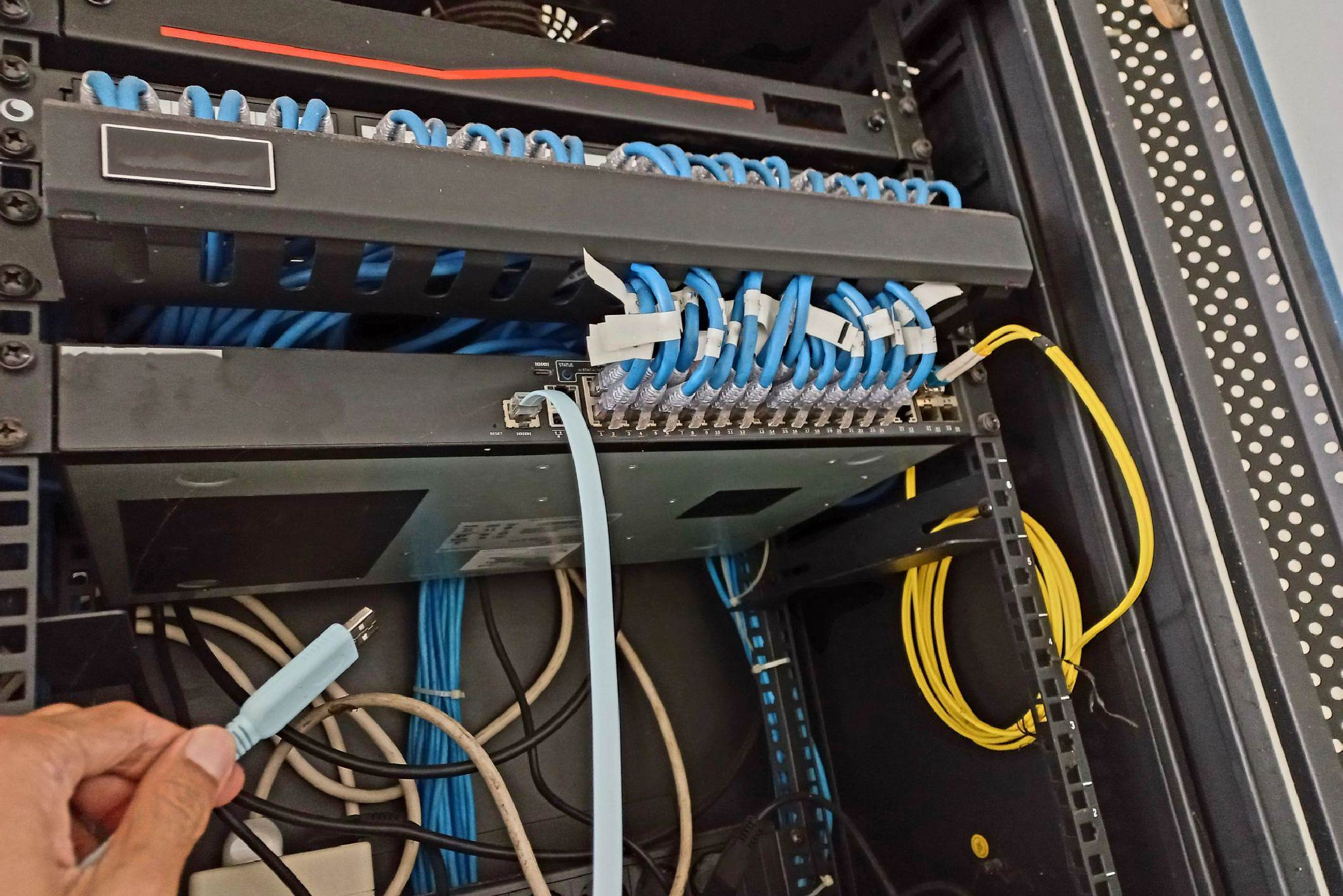 Network technician setting up and configuring router switch using console cable.